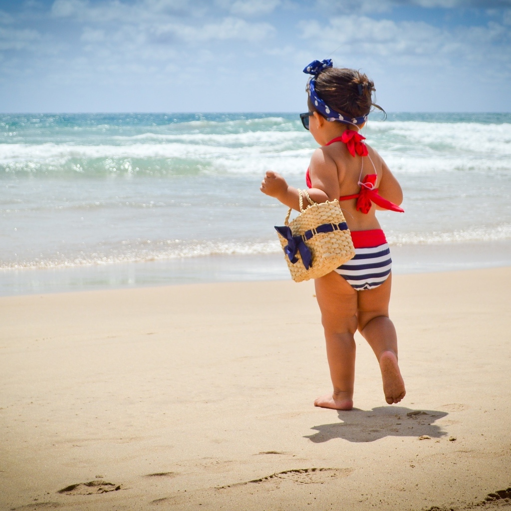 Модная маленькая девочка с сумочкой на берегу моря