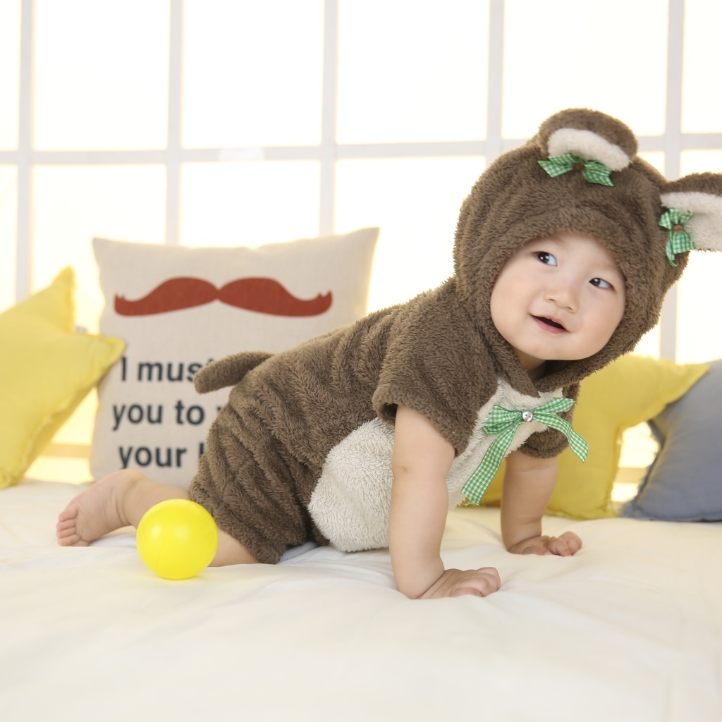 Смешной ребенок азиат в костюме на кровати