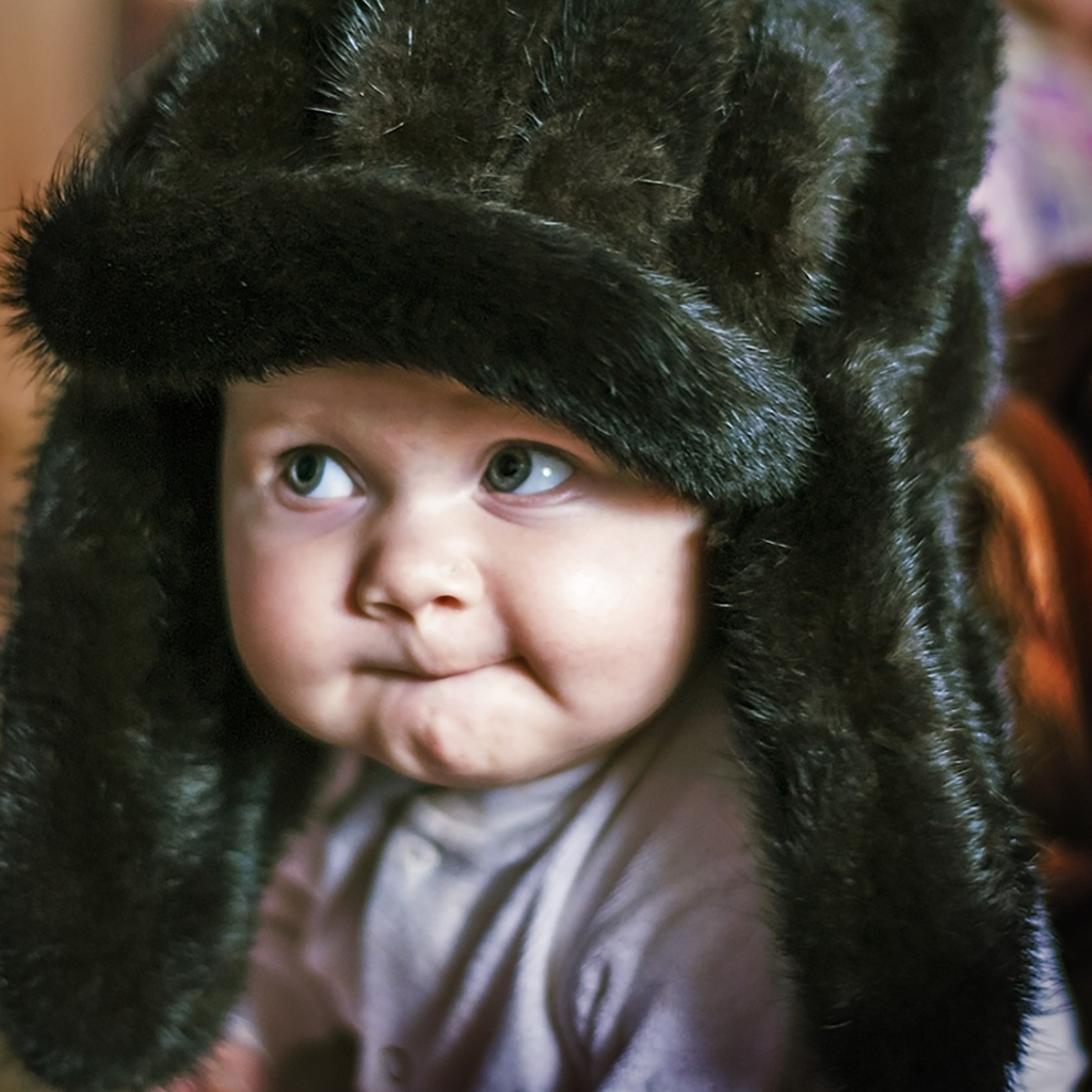 Смешной ребенок в черной меховой шапке