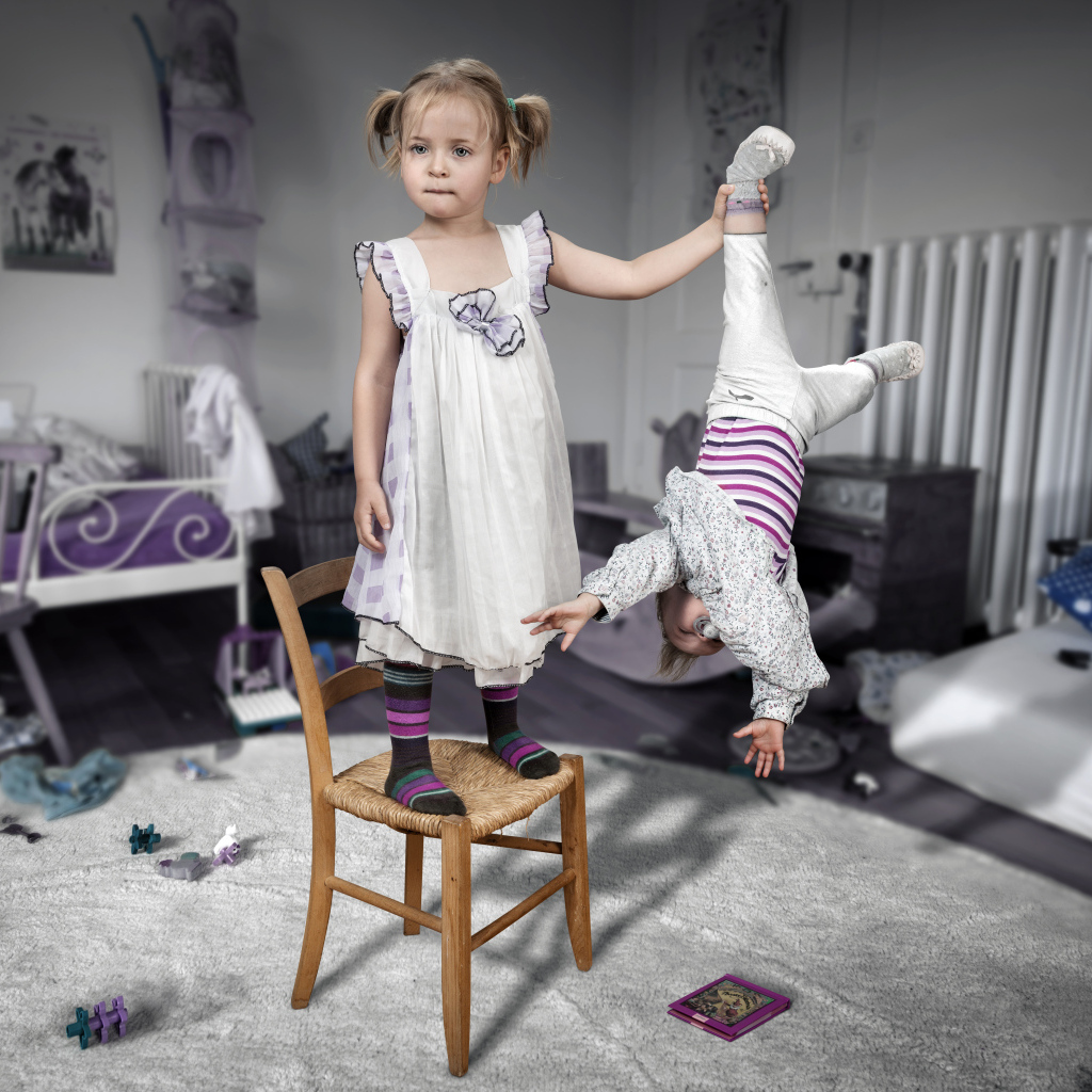 Девочка держит маленького брата за ногу