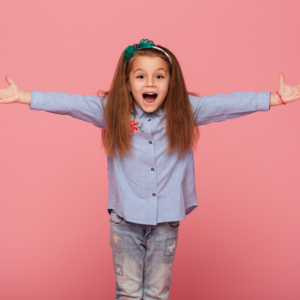 Счастливая маленькая девочка на розовом фоне