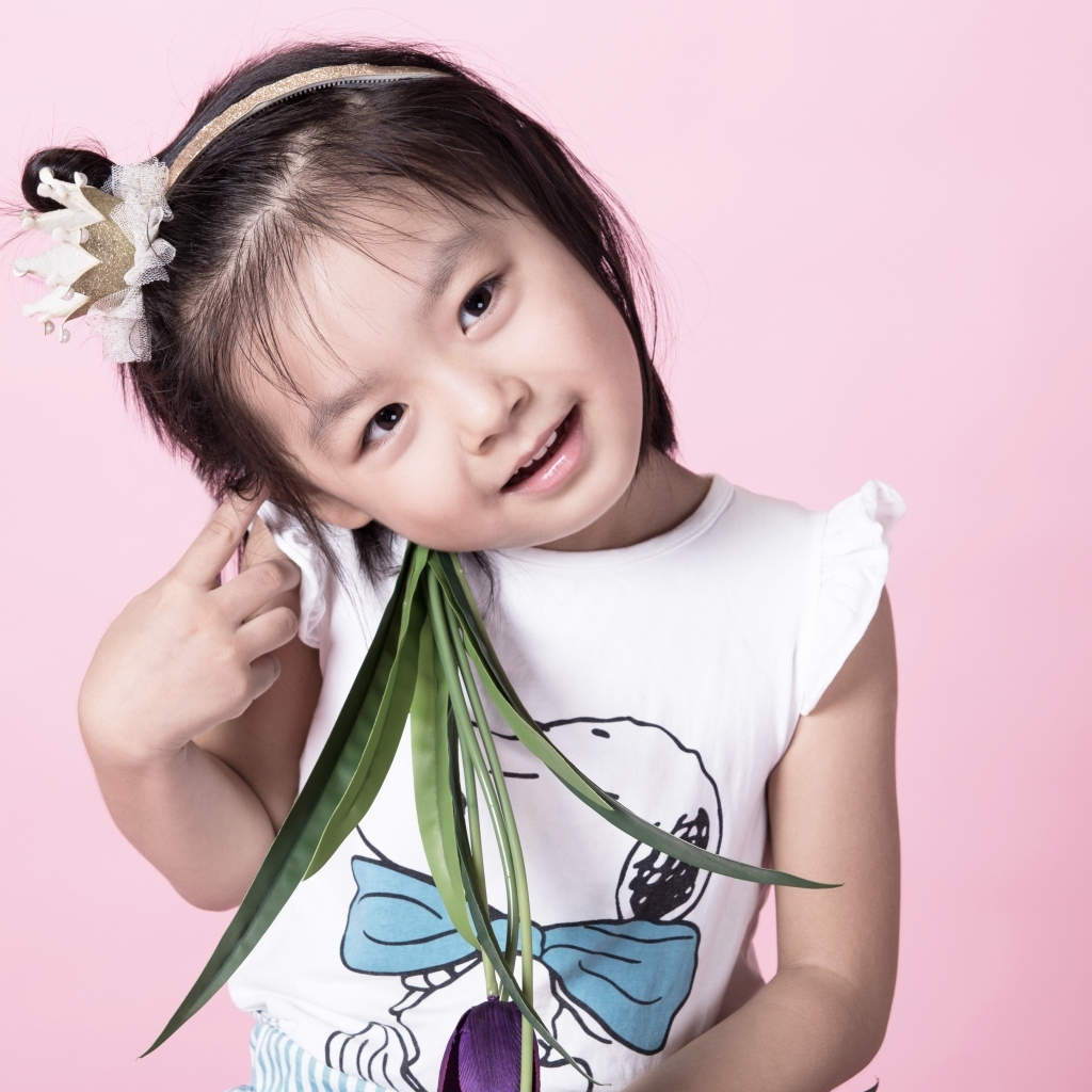 Маленькая девочка азиатка на розовом фоне