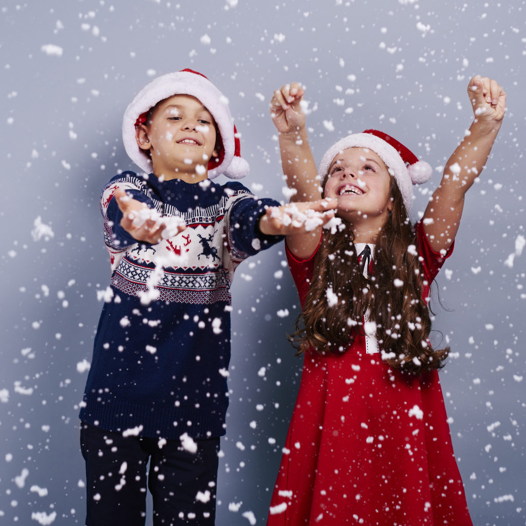 Маленькие мальчик и девочка ловят снег