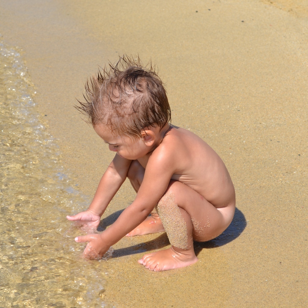 Маленький мальчик на пляже у моря на песке