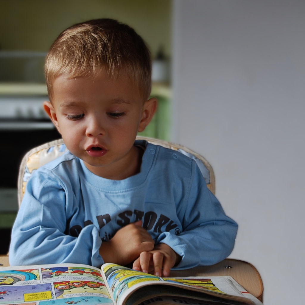 Маленький мальчик читает интересную книгу