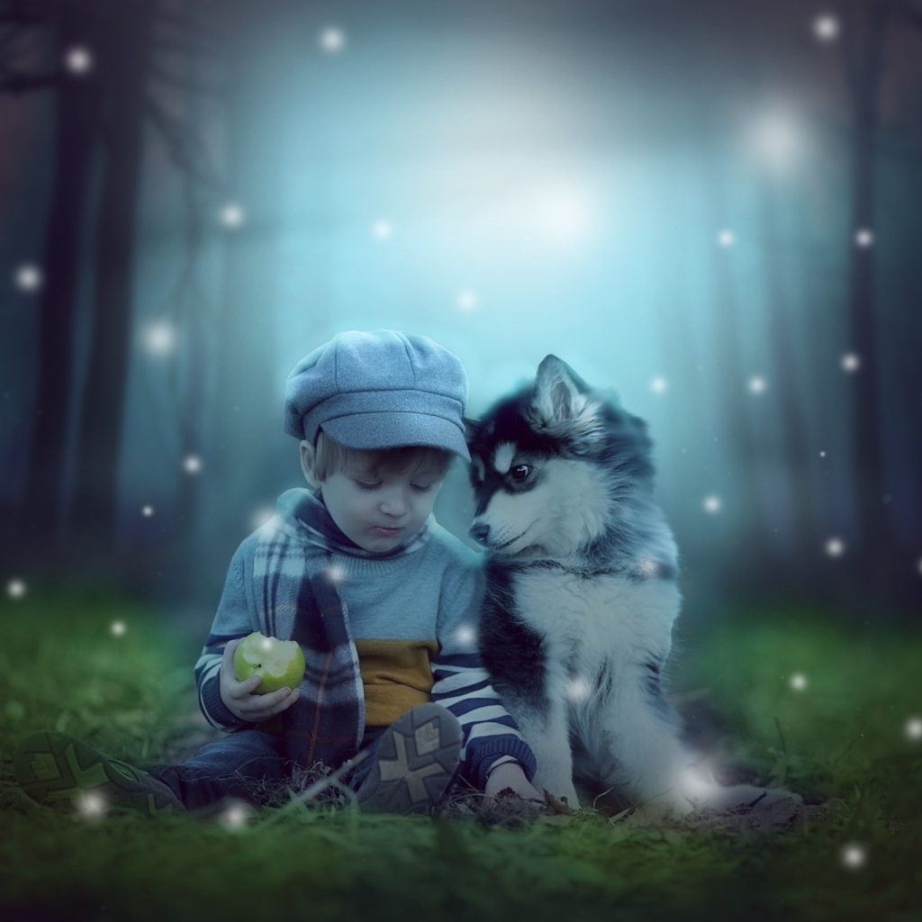 Маленький мальчик с щенком сидят на траве в лесу