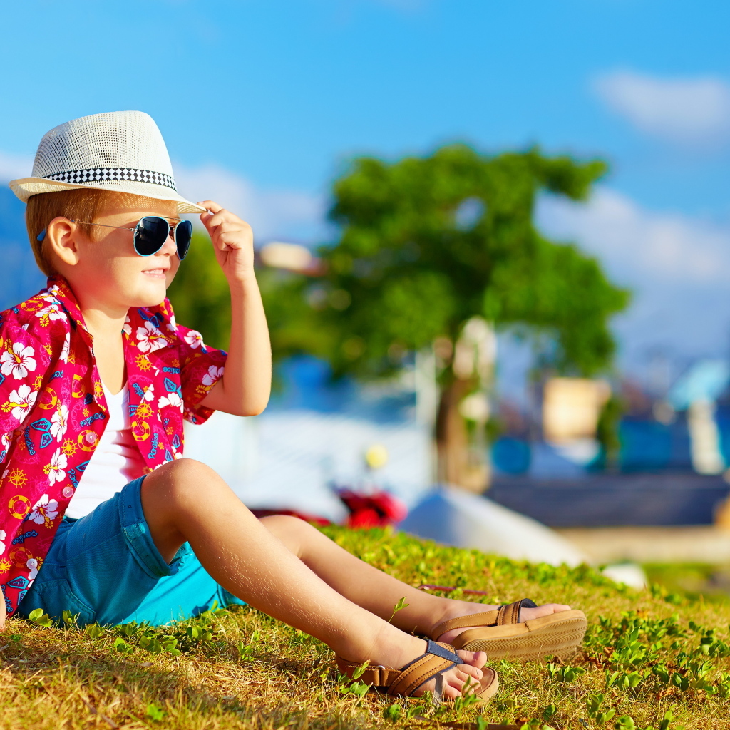 Маленький мальчик в очках и шляпе в лучах солнца