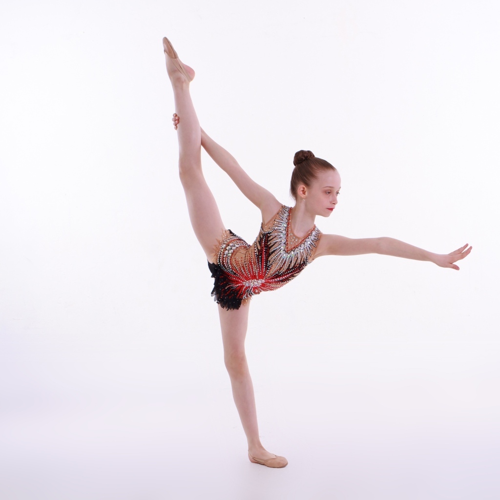 Маленькая девочка гимнастка на белом фоне