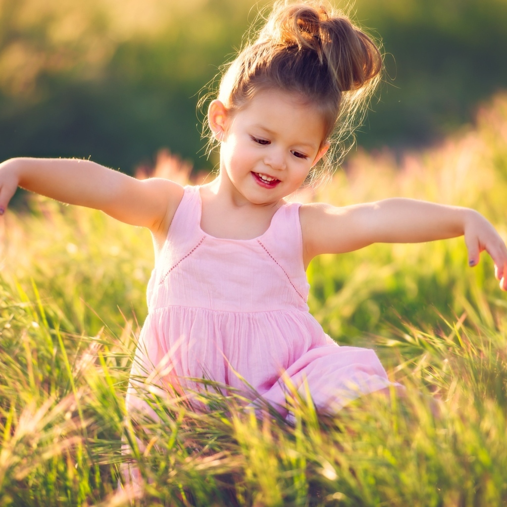 Маленькая девочка в розовом платье в зеленой траве