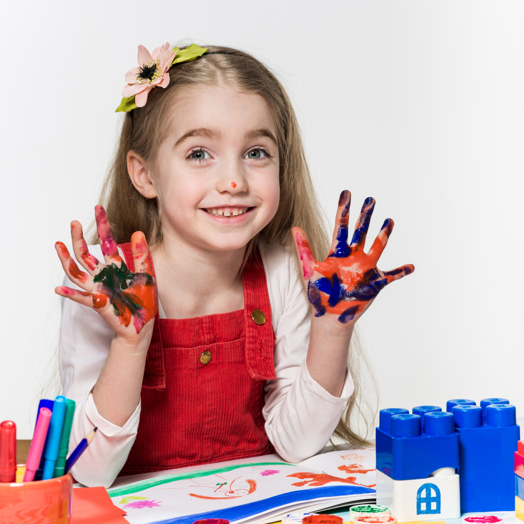 Маленькая девочка рисует красками