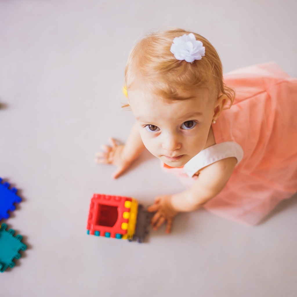 Маленькая девочка играет на полу с конструктором