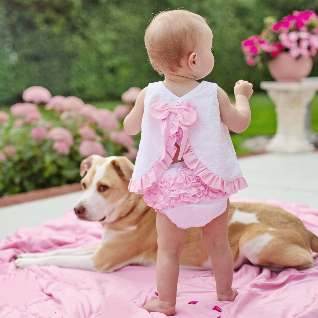 Маленькая девочка с собакой на розовом покрывале
