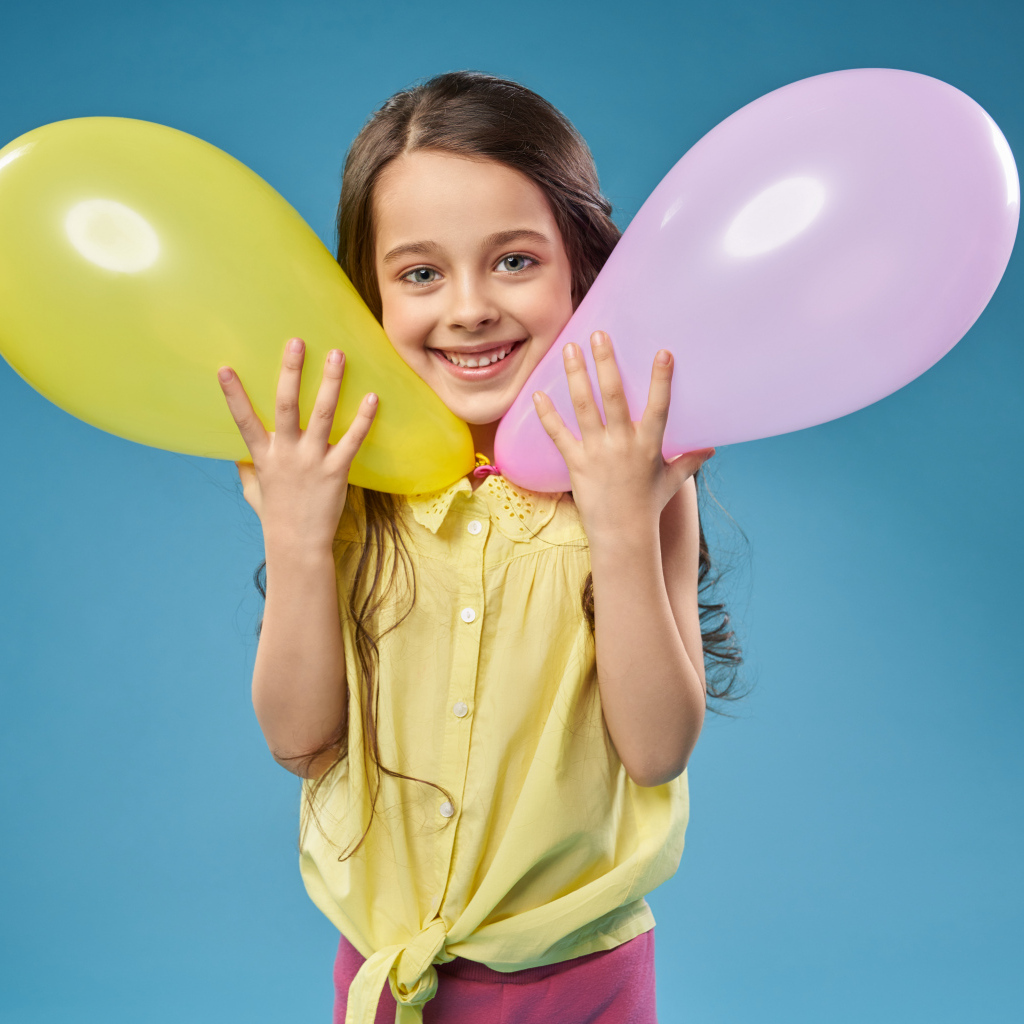Маленькая девочка с воздушными шариками на голубом фоне
