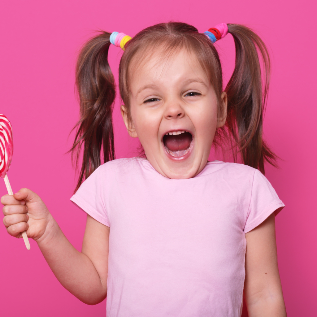 Маленькая девочка с леденцом на розовом фоне