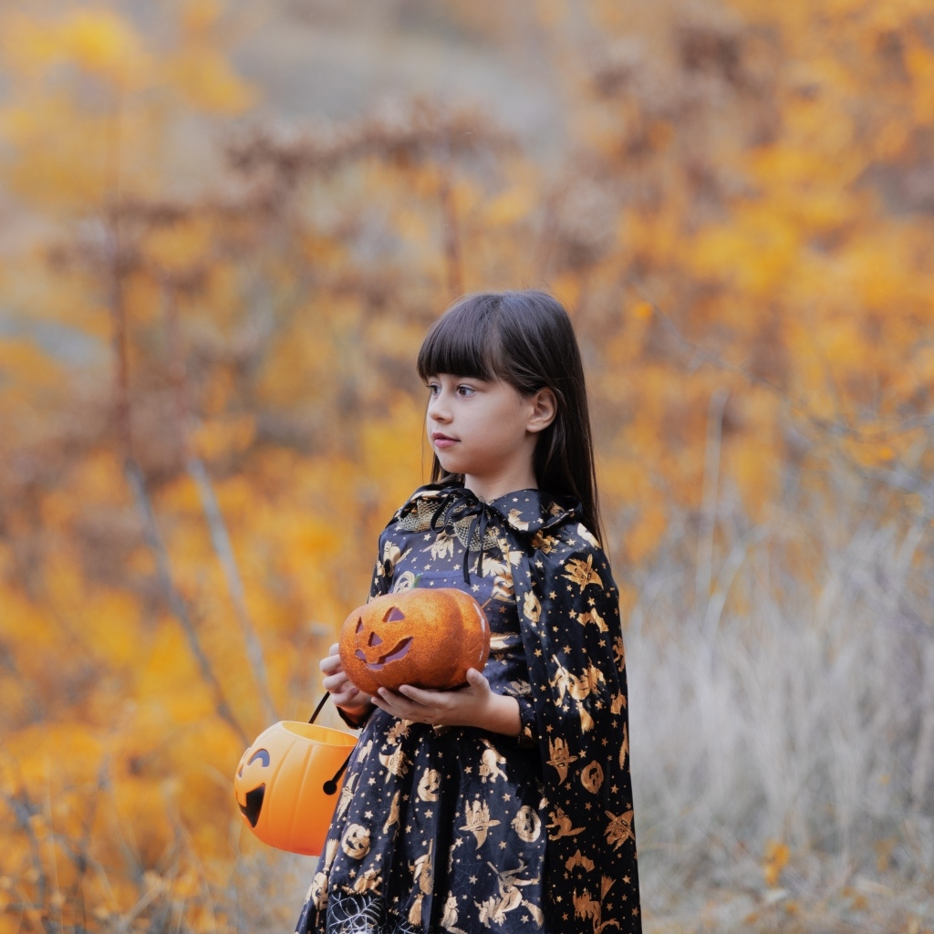 Маленькая девочка с тыквами в осеннем парке