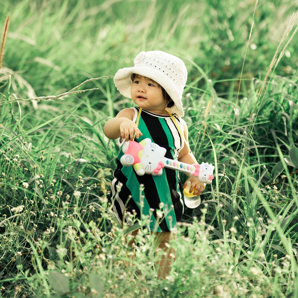 Маленькая девочка с игрушечной гитарой в траве