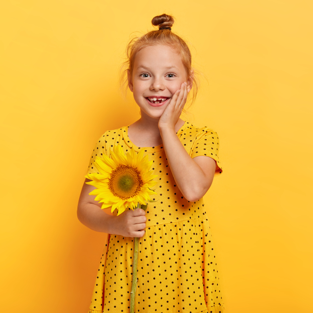 Маленькая рыжеволосая девочка с подсолнухом в руках