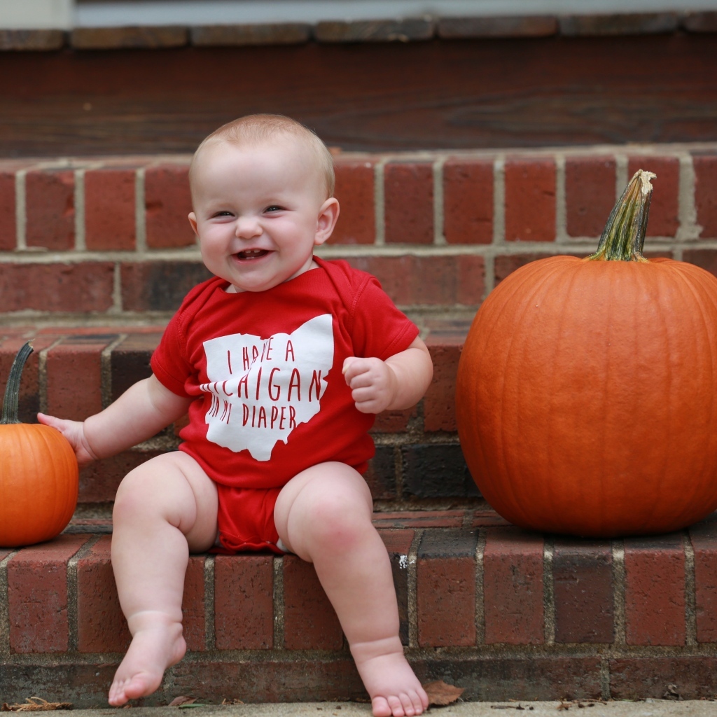 Маленький улыбающийся ребенок с тыквами на ступенях