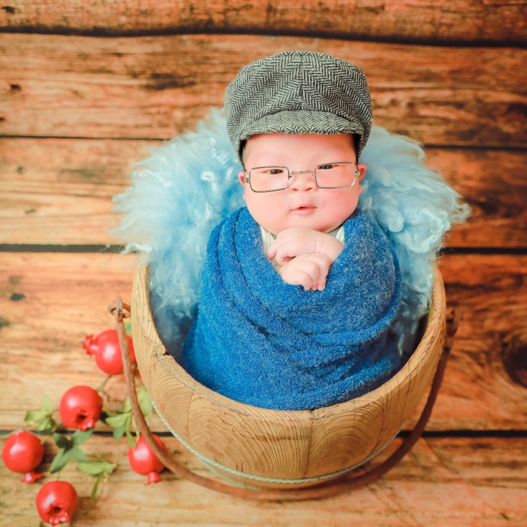 Новорожденный малыш в покрывале с кепкой на голове