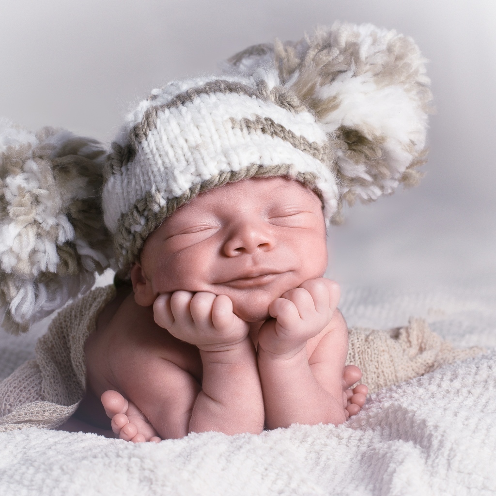 Новорожденный младенец в большой вязаной шапке