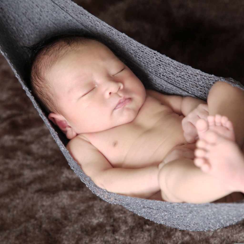 Новорожденный спящий малыш в вязаном гамаке