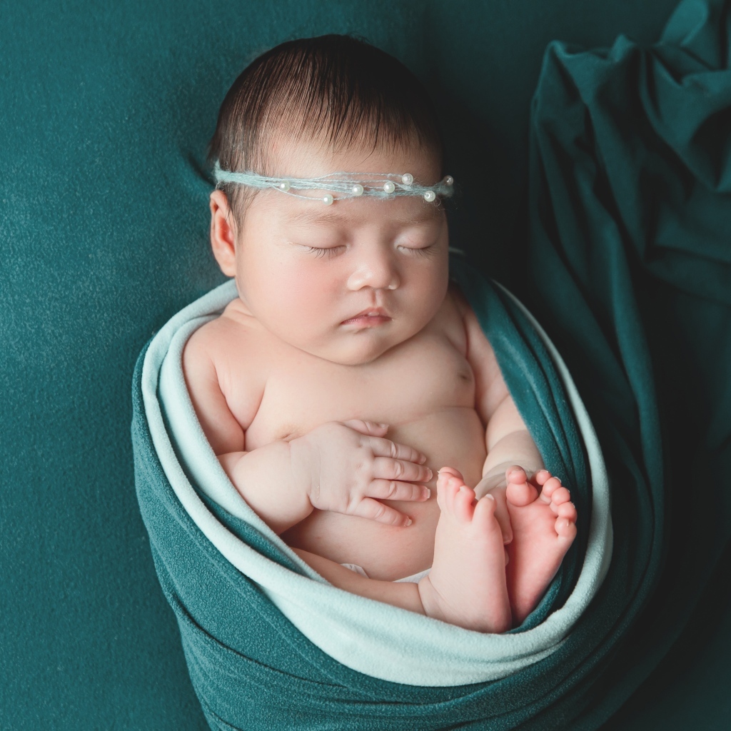 Фотография спящей новорожденной девочки на зеленом фоне