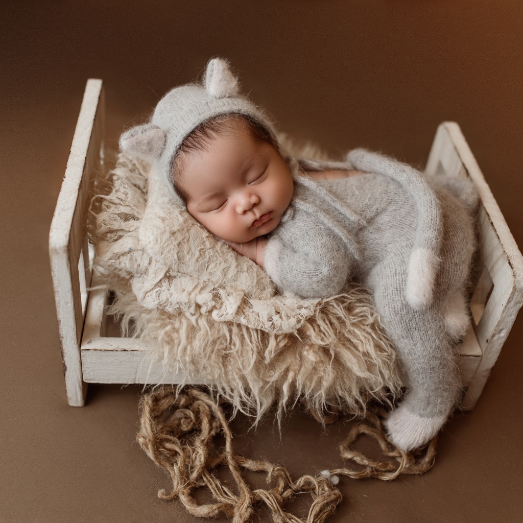 Спящий ребенок на маленькой кровати на коричневом фоне