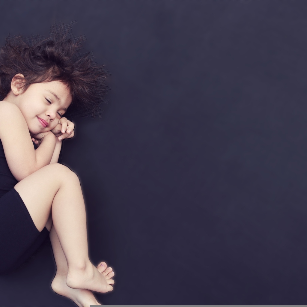 Спящая маленькая девочка на сером фоне