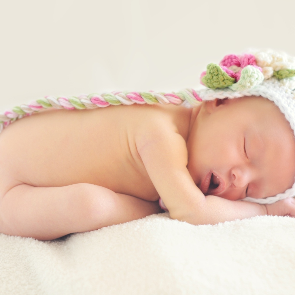 Спящая новорожденная девочка с вязаной шапке