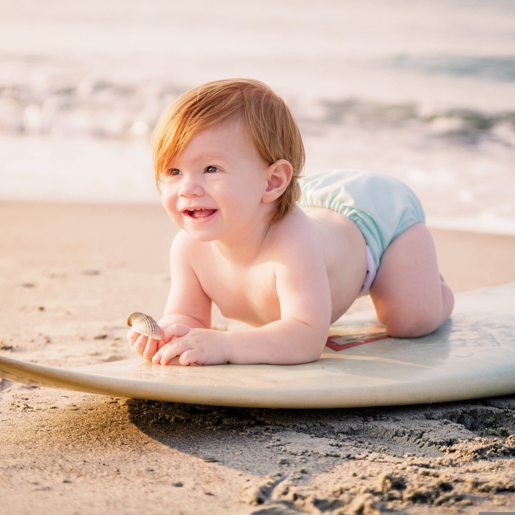 Улыбающийся ребенок с доской для серфинга на пляже