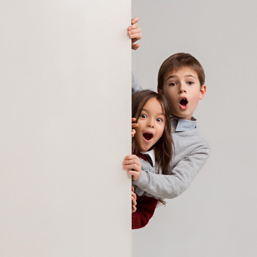 Удивленные дети выглядывают из-за угла