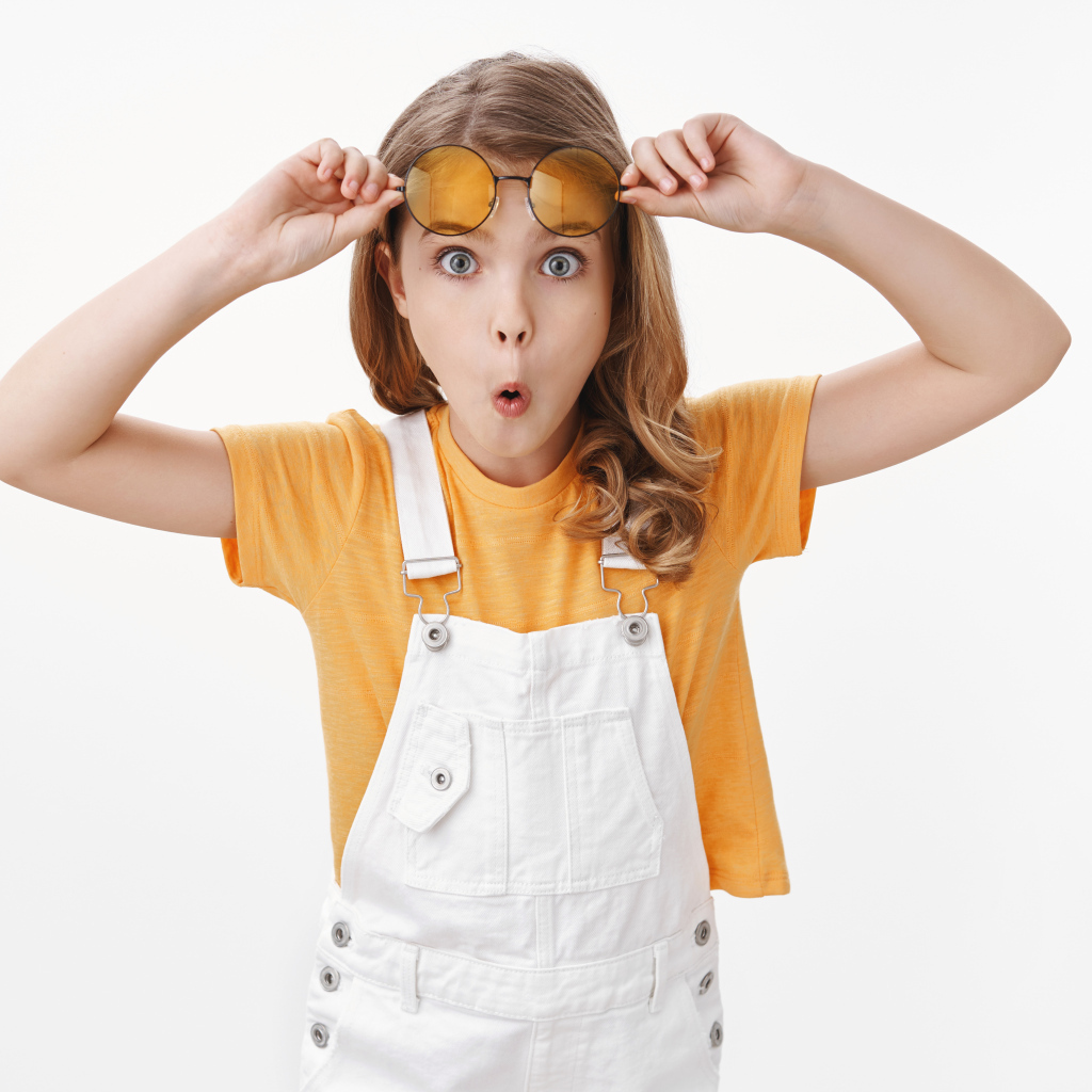 Удивленная девочка в очках на белом фоне