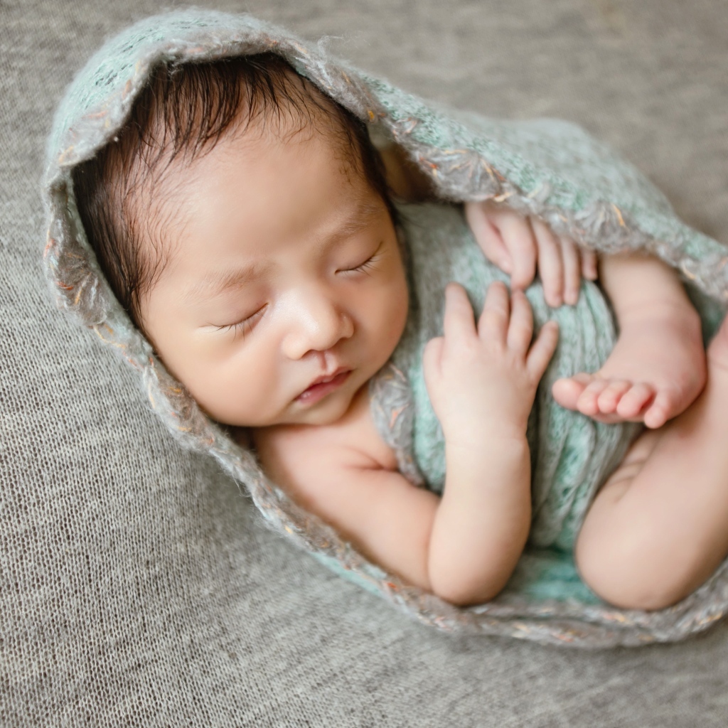 Крошечный новорожденный малыш на сером фоне