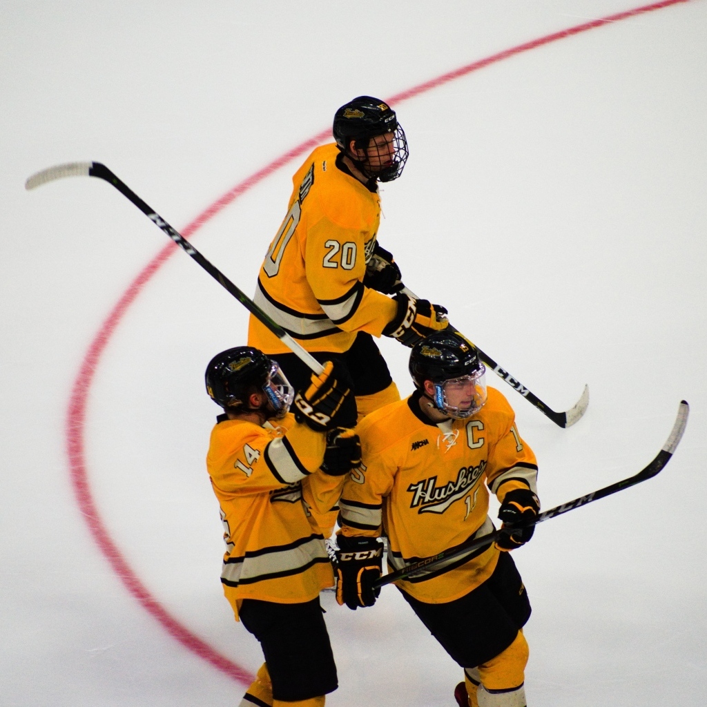 Три хоккеиста с клюшками на льду