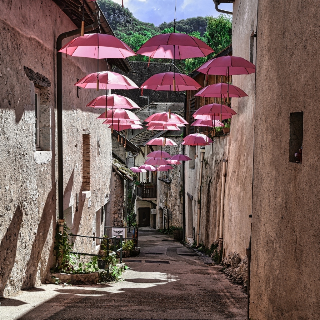 Розовые зонтики украшают узкую улицу