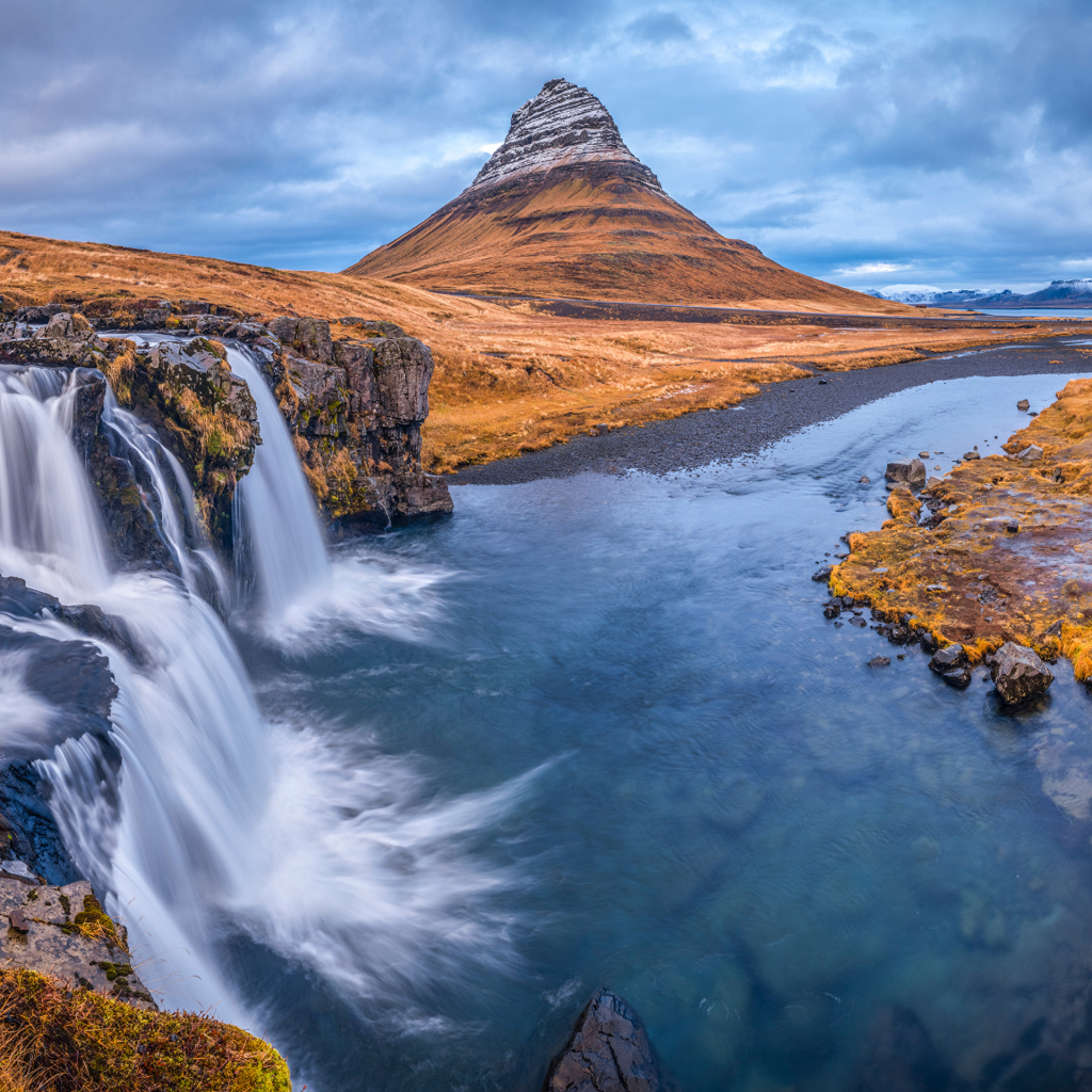 Вид на реку, водопад и гору Киркьюфетль под пасмурным небом Исладнии