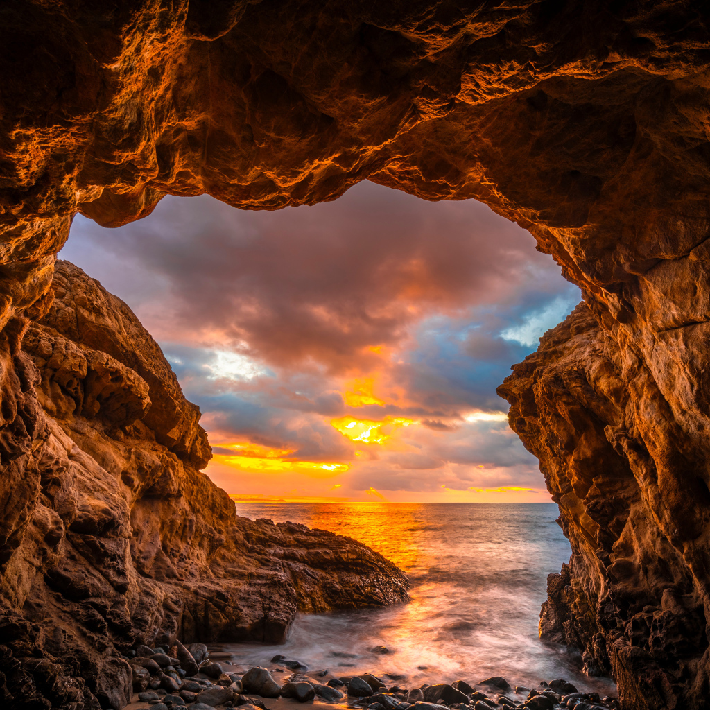 Арка в горе на закате солнца на пляже Малибу, США