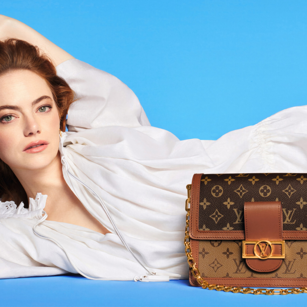 Актриса Эмма Стоун с сумочкой Louis Vuitton на голубом фоне