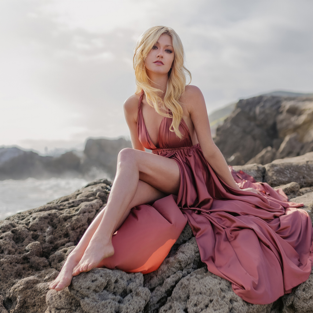 Актриса Кэтрин Макнамара сидит на камне у моря