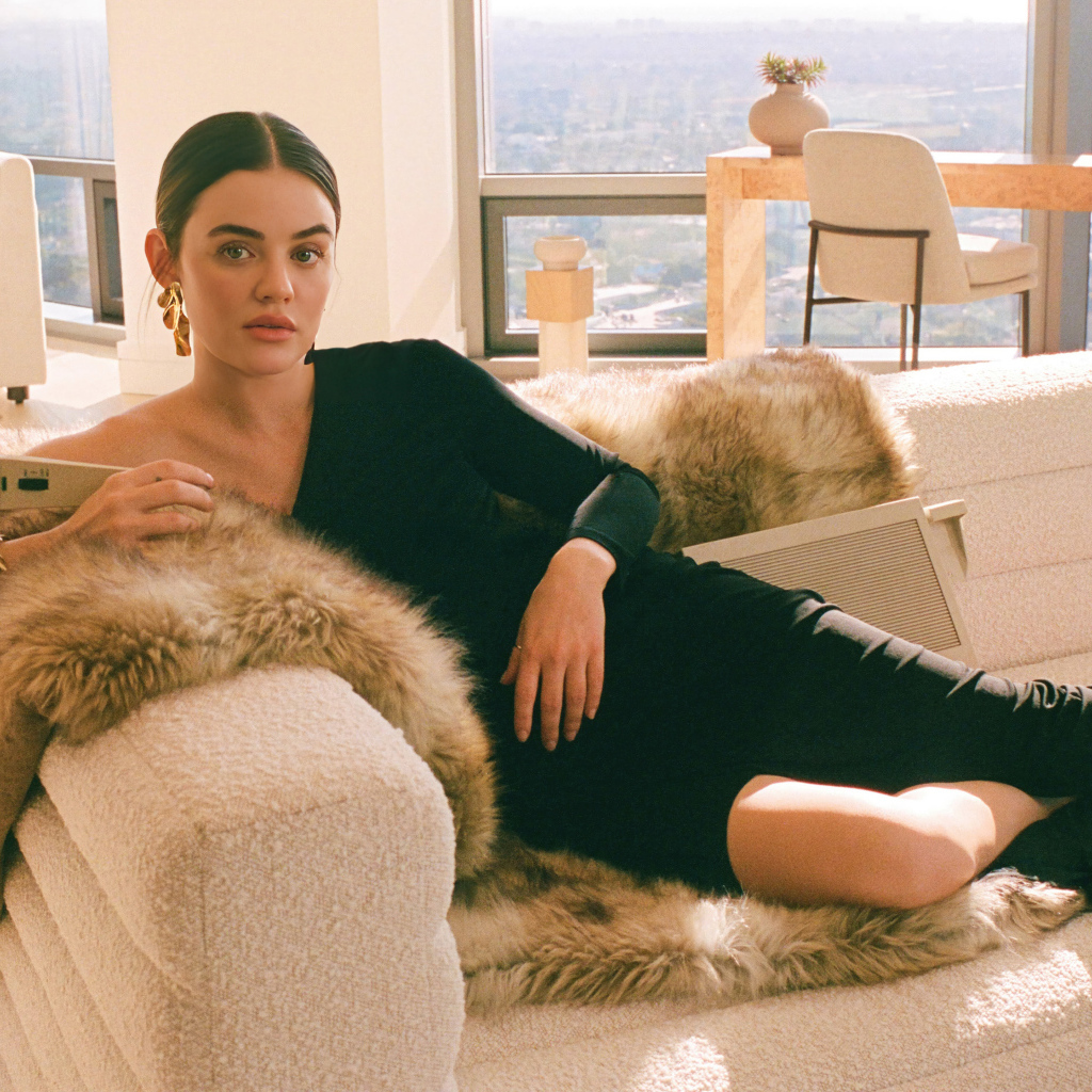 Актриса Люси Хейл в черном платье лежит на диване