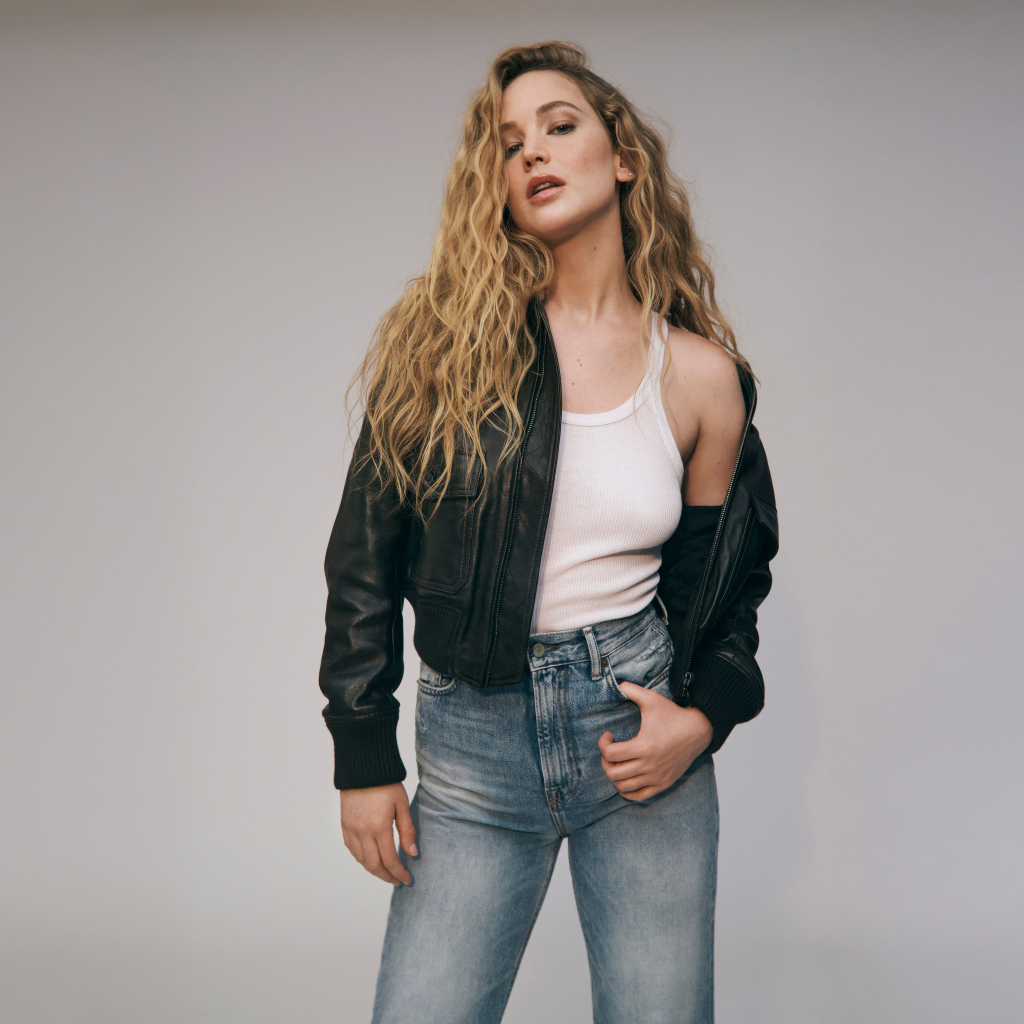 Американская актриса Дженнифер Лоуренс  в джинсах на сером фоне