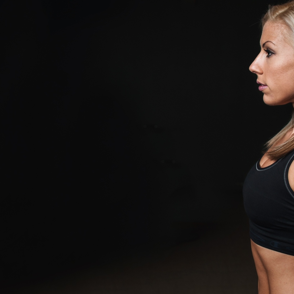 Спортивная блондинка стоит на черном фоне