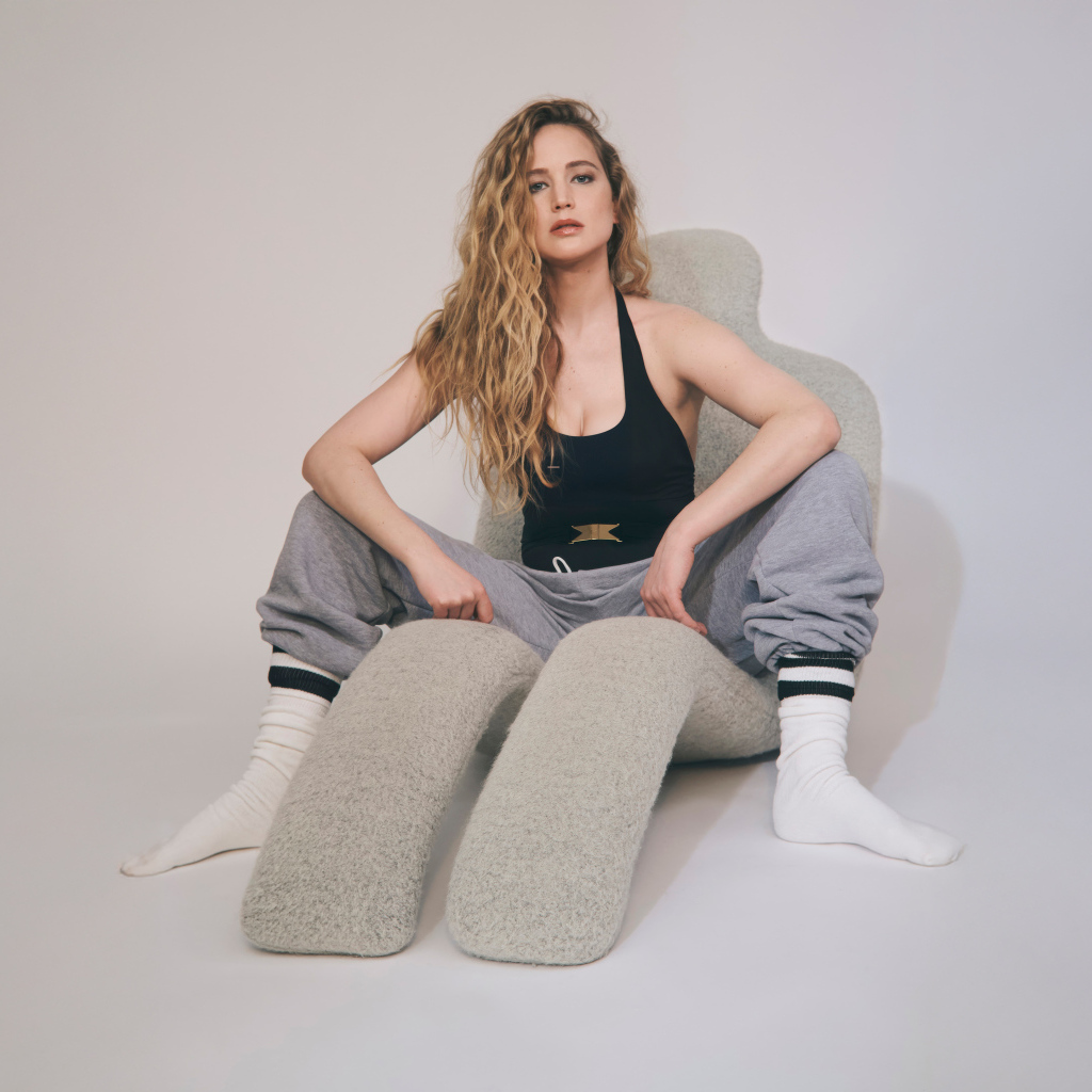 Красивая актриса Дженнифер Лоуренс  сидит на сером кресле