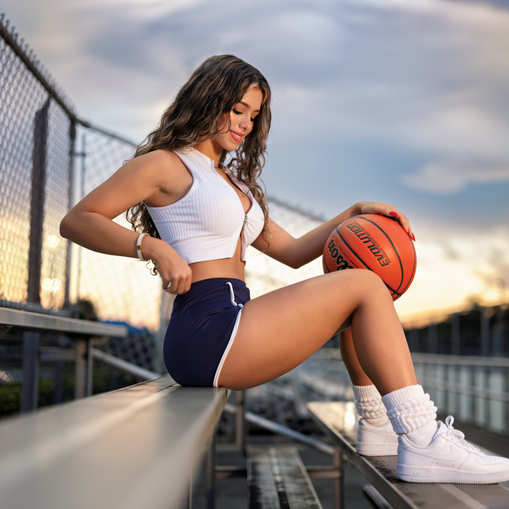 Улыбающаяся спортивная девушка с баскетбольным мячом