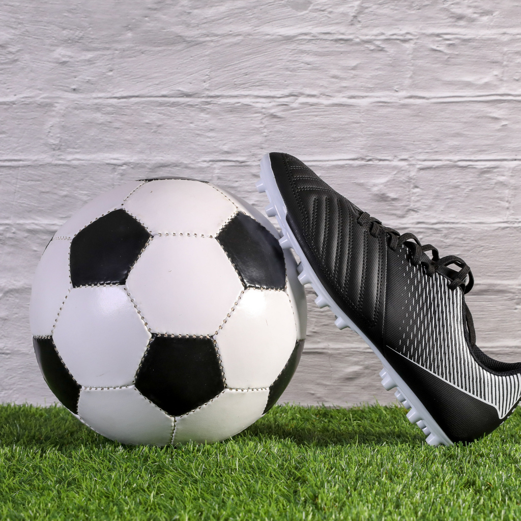 Футбольный мяч и спортивная обувь у стены