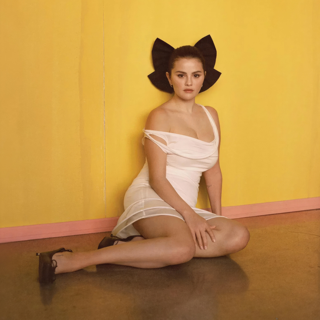 Молодая Селена Гомес сидит на полу у стены