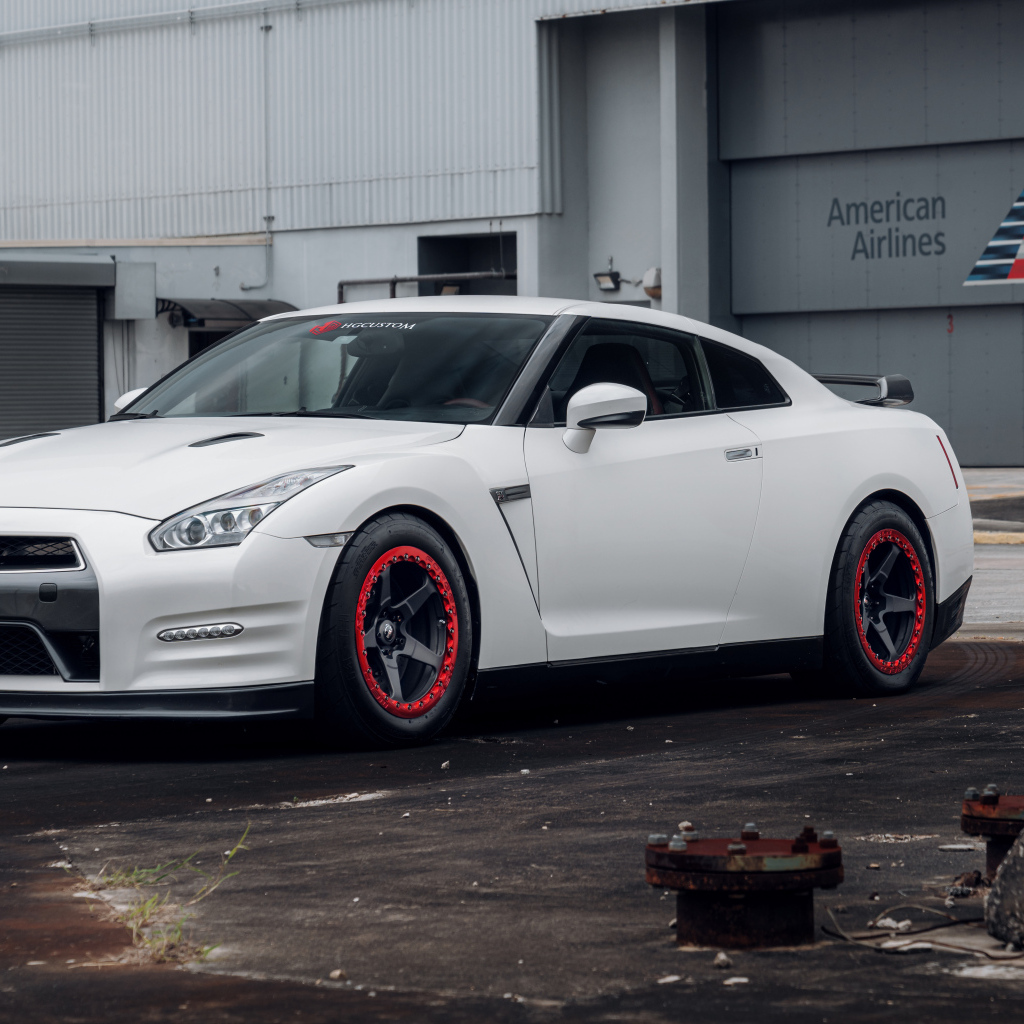 Белый автомобиль Nissan GT-R у гаража