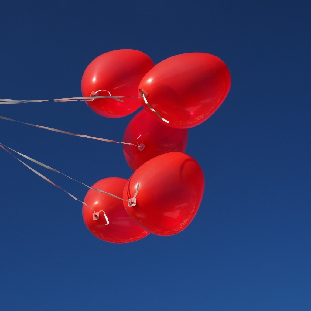 Красные воздушные шары на нитке на фоне голубого неба