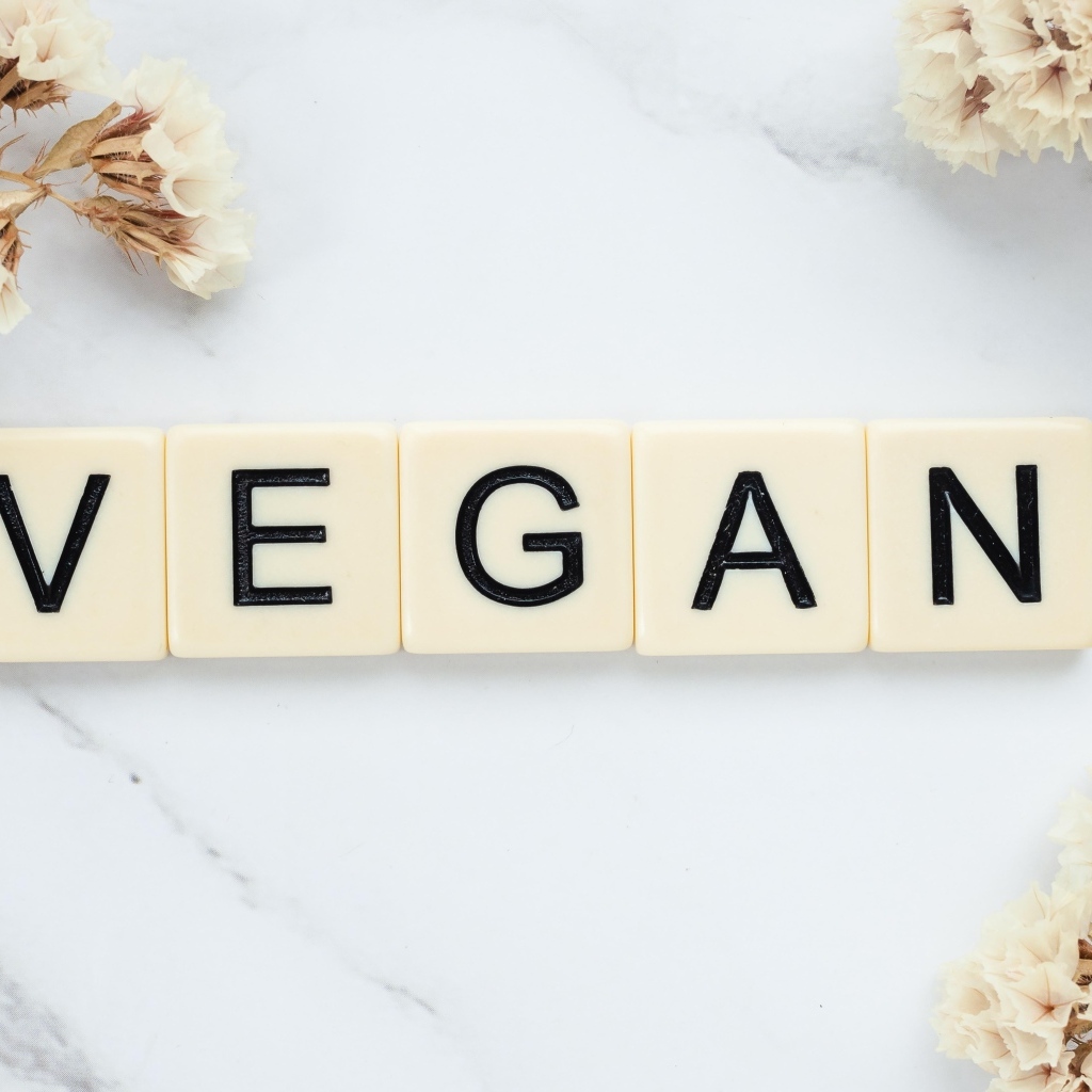 Надпись веган на столе с цветами