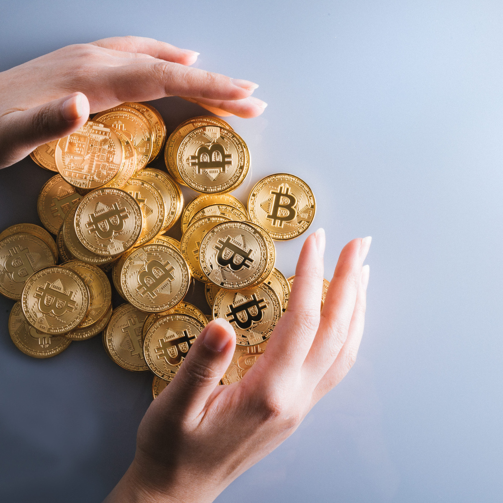 Много монет биткоин с руками на сером фоне